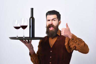 Kendine güvenen ve deneyimli bir garson. Yelek giyen genç adam tepsiyi tutuyor.