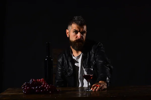 Дегустатор із суворим обличчям сидить за пляшкою вина та виноградом — стокове фото