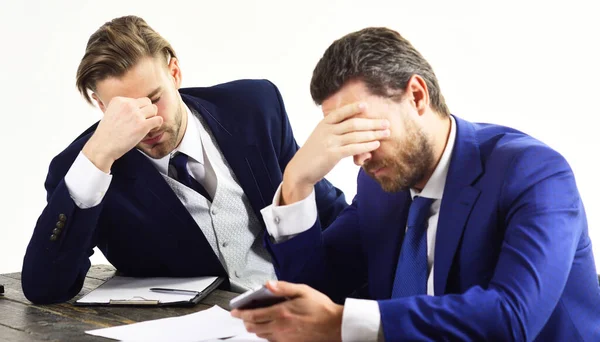 Men in with tired, worried faces read about business fail.