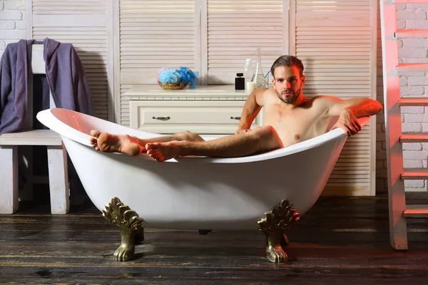 Macho sitzt in Badewanne mit Treppe und Stuhl im Hintergrund — Stockfoto