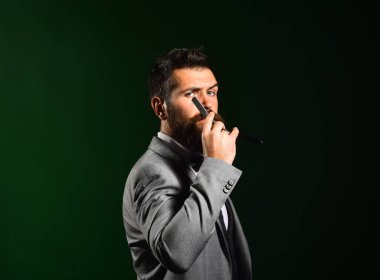 Koyu yeşil arka planda katı yüzlü bir iş adamı..