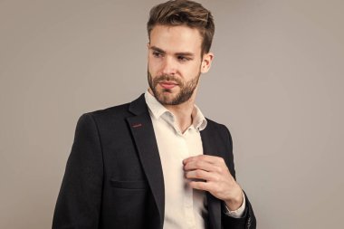 Flörtöz hissediyorum. Genç yönetici ofisinde. Gri arka planda bir iş adamının portresi. Kendine güvenen iş adamı portresi. Yakışıklı bir CEO portresi. Takım elbiseli bir iş adamı. Genç yakışıklı adam.