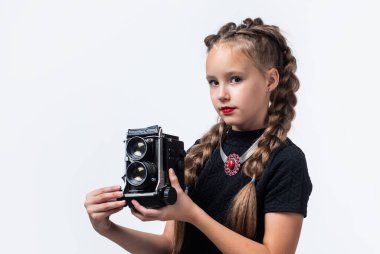 Yeni kameram. Geçmişi olan neşeli kız beyazda izole edilmiş görünüyor. Çocuk modası. Çocuk retro kamerayla fotoğraf çekiyor. Güzellik ve moda. Gazeteci ya da muhabir fotoğrafları. çocukluk mutluluğu