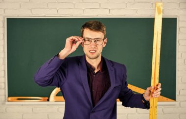 Elinde cetvel olan öğretmen okula geri döndü.