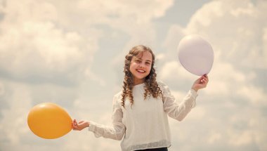 Mavi gökyüzü arka planında renkli balonları olan mutlu çocuk. Olumlu duygularını ifade et. Eğlenmene bak. Özgürlük. Yaz tatili kutlaması. Uluslararası Çocuk Günü. Komik fikir.