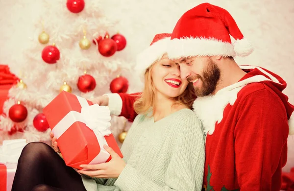 Αγαπώντας ζευγάρι αγκαλιά χαμογελώντας ενώ ξεπακετάρισμα δώρα με φόντο χριστουγεννιάτικο δέντρο. Ζευγάρι ερωτευμένο απολαμβάνει τις γιορτές των Χριστουγέννων. Οικογενειακή Χριστουγεννιάτικη παράδοση. Γιορτάζουμε μαζί τα Χριστούγεννα — Φωτογραφία Αρχείου