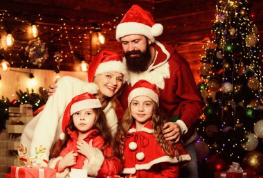 Yeni yıl partisinin tadını çıkarıyorum. Noel Baba şapkalı küçük çocuklar ve ebeveynler. Mutlu noeller. Anne ve baba çocukları sever. Portre seven aile. Bir sürü Noel hediyesi kutusu var. Mutlu aile yeni yılı kutluyor.