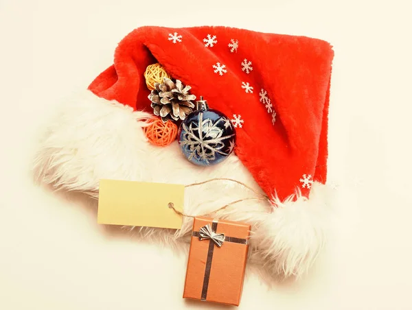 Udržujte rodinné tradice. Vánoční dárky od Santy. Atributy zimních prázdnin. Nový rok a vánoční oslavy. Santa červená klobouk bílé pozadí horní pohled. Santa klobouk s vánoční dárkovou krabicí — Stock fotografie