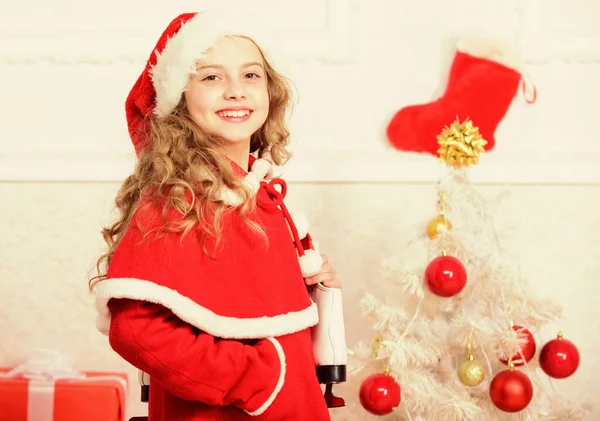 Парень возле рождественской елки держит зимние коньки. Маленькая девочка удовлетворила рождественский подарок. Лучший подарок на свете. Конькобежный спорт. Зимняя активность. Зимний отдых. С Новым годом! — стоковое фото