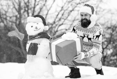 Kış tatili Adam kardan adam yaptı. Noel Baba şapkalı adam dışarıda eğleniyor. Adam gülen surat, karlı doğa geçmişi. Sakallı hippi hediye kutusu. Sürpriz konsept. Kış oyunları. Kış etkinliği