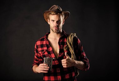 Batı kültürü. Batı hayatı. Şapka tutan ip ve matara giyen adam. Amerikan kovboyunun kementi. Yakışıklı, traşsız, siyah bir kovboy. Şerif kavramı. Vahşi kovboy alkol içiyor.