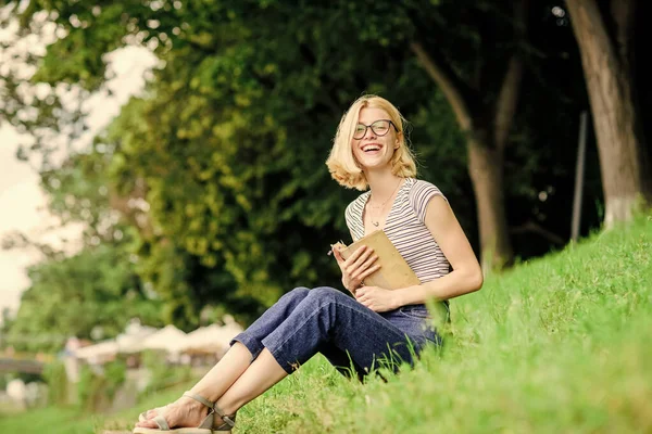 Summer vacation. Student smart nerd sit on green grass and read book. Woman dreaming about vacation. Literature for summer vacation. Girl relaxing at riverside after working day. Rest relax and hobby