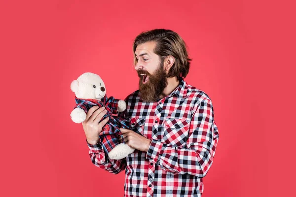 Бородатый и стильный. С Днем Святого Валентина. удивленный бородач держит плюшевого мишку. мужчина играет с медведем. жестокий взрослый хипстер играет с игрушкой. С днем рождения. быть в хорошем настроении — стоковое фото