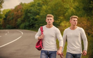 Uzun bir yol. Macera konsepti. Yolda otostop çeken adamlar. Turist gezgini otomobil durağında durur. Taşıma sorunları. Erkekler sırt çantasıyla yürüme yolu. İkizler yol boyunca yürür. Kardeş arkadaşlar doğa geçmişi