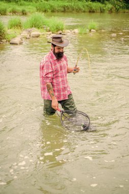 Balık Bağımlılığı. Yaz haftasonu. Büyük balık avı. Elinde olta olan balıkçı. Olgun adam balık tutuyor. Balık tutan adam. Hobi ve spor aktiviteleri. Pothunter. Sudaki sakallı balıkçı
