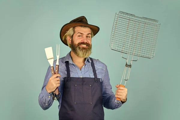 Penair picknick. Een man met een baard. Gereedschap voor het roosteren van vlees buiten. Picknick en barbecue. Klaar voor barbecue feestje. Culinair concept. Zomers weekend. gelukkig hipster hold kookgerei voor barbecue — Stockfoto