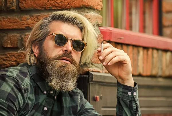 Homem fumando ao ar livre. Homem maduro na moda fumando cigarro. Homem hipster punk a fumar. Tabagismo e hábito. fumo passivo ou passivo. brutal caucasiano masculino em óculos — Fotografia de Stock