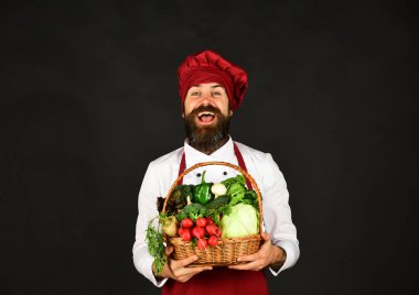 Sakallı adam siyah arka planda sebze tutuyor..