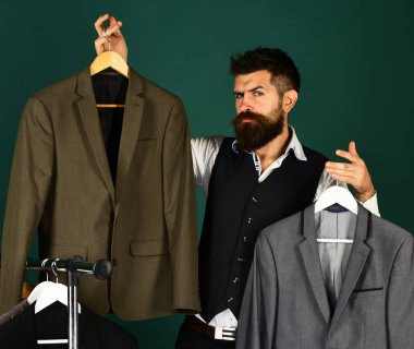 Elbise rafında sakallı bir adam. Resmi kıyafet seçimi.