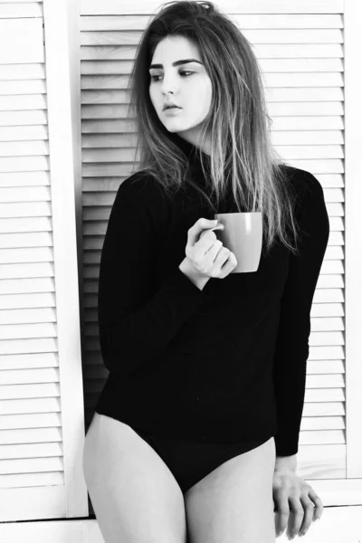 Jolie fille sexy mignonne posant en body noir avec tasse — Photo