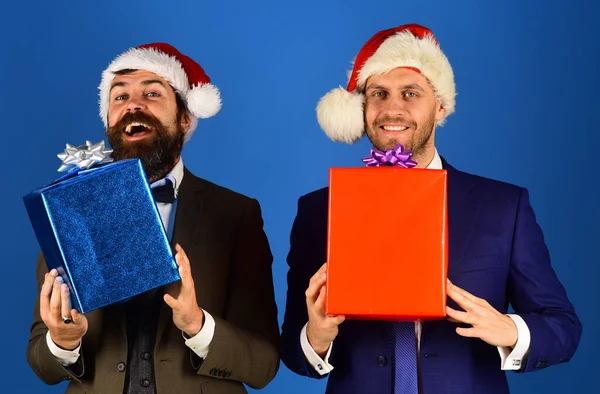 Mężczyźni w eleganckich garniturach i kapeluszach Santa na niebieskim tle. — Zdjęcie stockowe