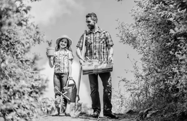 Trädgårdsskötsel. Vårens trädgårdschecklista. Far och dotter med spade och vattenkanna. Det är dags att plantera bäddar och vårda gräsmattan. Välj ut lägenheter favorit växter. Trädgårdsproffs — Stockfoto