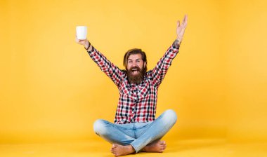 Mutlu, sakallı, sakalsız, şık saçlı, sıradan kıyafetler giyen, kahve içen, başarılı bir adam.