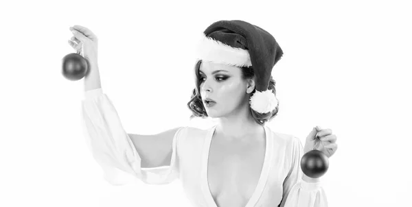 Donna indossare abito sexy e cappello di Babbo Natale tenere palle decorative su sfondo bianco. Ragazza con trucco e acconciatura pronta per la festa di Natale. Trucco e outfit per la festa di Natale. Preparati per Natale. — Foto Stock