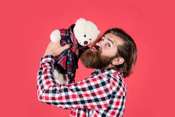 Brutal barbudo hombre desgaste a cuadros camisa tener exuberante barba y bigote beso peluche oso juguete, amor —  Fotos de Stock