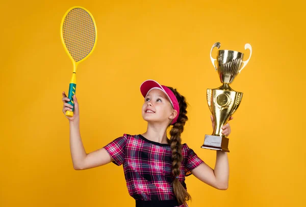 Kazanan çocuk raket ve şampiyonlar kupasıyla. Genç kız tenis şampiyonluğunu kazandı. Spor. Tenis ya da badminton oyuncusu. Sağlıklı ve aktif bir yaşam tarzı. Enerji dolu. Mutlu çocukluk. çocuk raketi tut — Stok fotoğraf