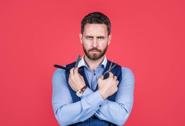 Sakallı adam, kırmızı arka planı kesmek ve traş etmek için eski berber aletlerini tut, berber.