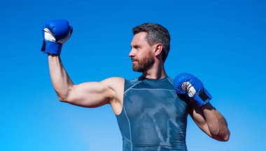 Güçlü boksör boks eldivenleriyle pazı kaslarını ve sporu gösteriyor.