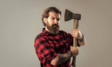 Kendine çok güveniyorsun. Baltası olan sakallı bir oduncu. Ekose gömlekli bir oduncu. Oduncu, kırmızı kareli gömlekli, vahşi sakallı adam. Tıraş konsepti. Cadılar Bayramı. Adam elinde bir balta tutuyor.