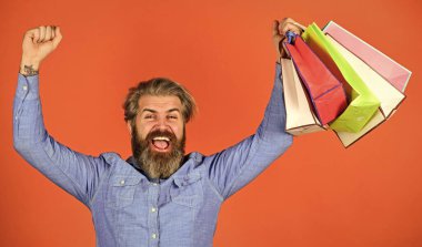Kaliteli hizmet. Neşeli adam çevrimiçi alışveriş yapmaktan hoşlanıyor. Alışverişten sonra mutlu hipster. Sakallı vahşi adam paketleri tutuyor. Tatilleri kutlamaya hazır. Erkek moda satışı. Satın almada tasarruf