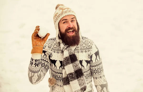 Homme souriant fond de neige. Jeux de neige. Amusez-vous bien. Joyeux chapeau barbu tricoté hipster et gants chauds jouent avec la neige à l'extérieur. Vacances de Noël. Faire de la boule de neige. Concept de bonheur — Photo