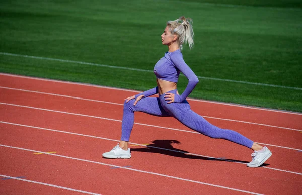 Sexy dame sportive étirement et échauffement dans les vêtements de sport sur la piste de course du stade, soins de santé — Photo