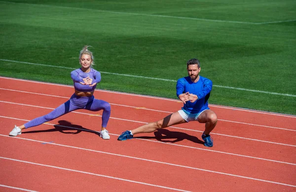 Estilo de vida saudável. flexibilidade muscular. casal esporte alongamento. parceiros de fitness aquecendo. homem atlético e mulher sexy formação. treinador masculino e feminino no estádio do squat lunge — Fotografia de Stock