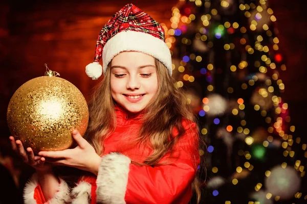 Ambiente festivo el día de Navidad. Chica traje de Santa Claus celebrar grandes adornos árbol de navidad bola. Decoraciones navideñas. Me encanta decorar todo a su alrededor. Brillante juguete grande. Feliz Navidad. —  Fotos de Stock