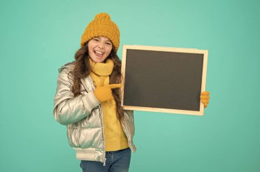 Çocuk toplumunu bilgilendirmek. Tahtası olan çocuk. Ürün tanıtımı. Çocuk tanıtım etkinliği. Terfi konsepti. Neşeli bir çocuk terfi ediyor. Gülümseyen kız kışlık kıyafet giyer boş karatahta fotokopi alanı gösterir