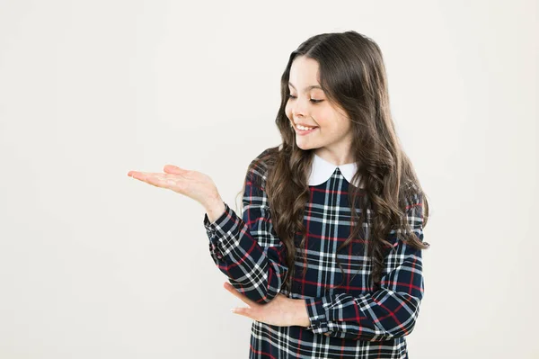 Beauty product. kid presenting product. child has long curly hair. after visit to hairdresser. happy schoolgirl in fashion uniform. back to school. small girl classy checkered dress. copy space — Stock Photo, Image