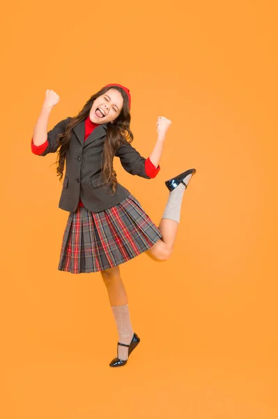 Щаслива маленька дівчинка в шкільній формі з виграшними жестами насолоджується святкуванням, стипендією — стокове фото