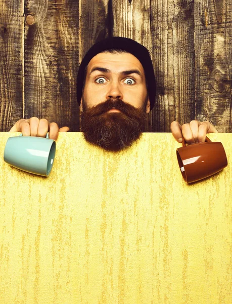 Barbudo brutal hipster caucásico con hoja de papel y tazas —  Fotos de Stock