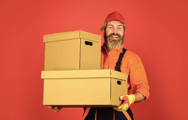 Yaşayan mükemmeliyet. Taşınma gününde yeni bir ev. Boilersuit kutular içinde insan inşaatçısı. Yeni daireye taşınıyorum. Mutlu adam karton kutu. Binanın içinde kutular taşıyordu. taşınan kutular açılıyor