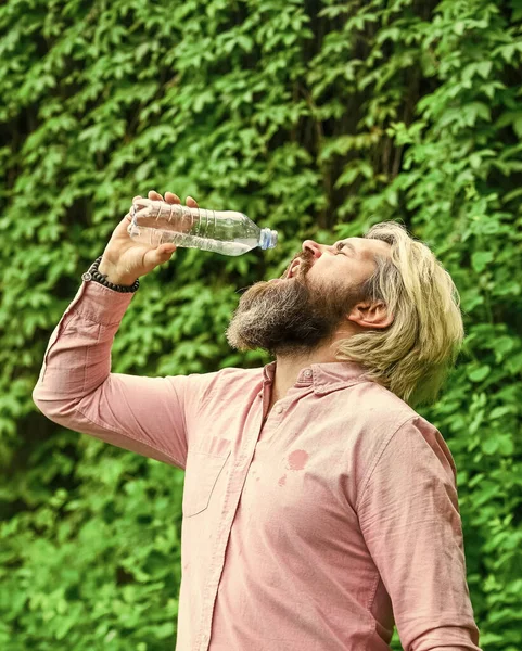 Törstig kille som dricker vatten på flaska. En hälsosam livsstil. Varmt väder. Uppfriskande lemonad. Sommarvärme. Läskvatten. Vattenbalans. Man skäggig turist dricksvatten plastflaska natur bakgrund — Stockfoto