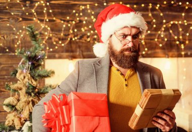 Teslimat, yılbaşı hediyesi. Noel hediyesi. Noel Baba şapkalı adam hediyesi. Teslimat servisi. Mutluluk ve neşe saçın. Sakallı adam Noel Baba şapkası takıyor ve hediye kutusu taşıyor. Noel ruhu burada.