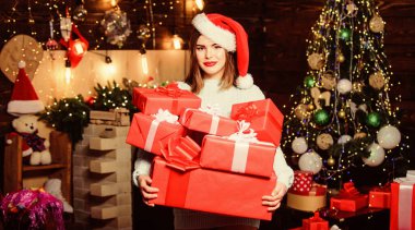 Sıcak Noel atmosferi. Noel arifesinde kadın Noel Baba şapkası. Başkasının hayatına büyü getirmek. Leydi Noel Baba Noel 'i evde kutluyor. Makyaj kırmızısı dudaklar bir sürü Noel hediyesi tutar.