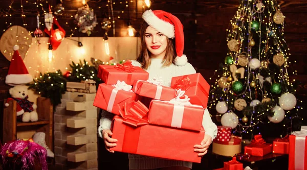 Ambiente acogedor de Navidad. Sombrero de Santa Claus mujer en Nochebuena. Traer magia a alguien más la vida. Lady Santa celebra la Navidad en casa. Chica elegante maquillaje labios rojos sostienen muchos regalos de Navidad — Foto de Stock