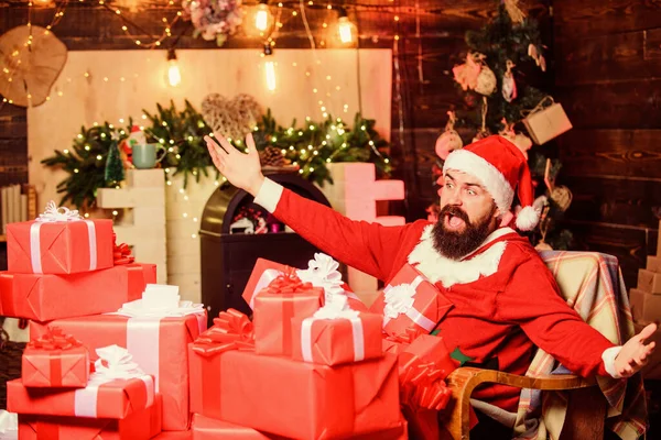 Привет от Санты. Бородатый мужчина сидит в кресле с кучей подарков. Дом Санта Клауса. Зимние каникулы. Уютная домашняя атмосфера. Посылки будут доставлены в пункт назначения. Отправка подарков — стоковое фото