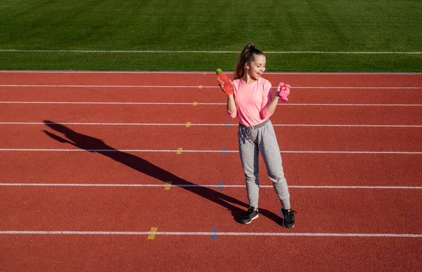 Adolescente chica entrenamiento con mancuernas y botella de agua en el estadio al aire libre, fitness — Foto de Stock