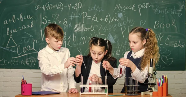 Niñas y niños proveyendo experimentos con líquidos. Tubos de ensayo con coloridas sustancias líquidas. Estudio de estados líquidos. Los alumnos de la escuela grupal con tubos de ensayo estudian líquidos químicos. Concepto científico —  Fotos de Stock